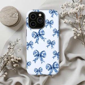 Könnte beinhalten: Eine weiße Handyhülle mit einem blauen und weißen Schleifenmuster. Die Hülle hat einen Ausschnitt für die Kamera und einen weißen Hintergrund.