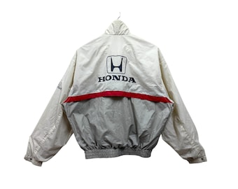 May include: A white jacket with a red and blue stripe across the chest. The jacket has the Honda logo on the front with the word "HONDA" underneath.