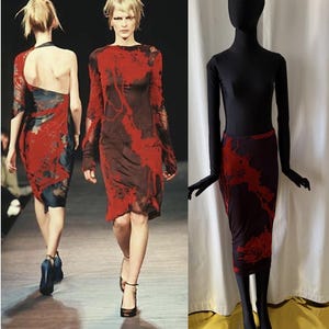 Op de afbeelding: Een rood en zwart patroon jurk en rok set. De jurk heeft lange mouwen en een knielange zoom. De rok heeft een vergelijkbaar patroon en lengte. De set wordt getoond op een mannequin en een model op een catwalk.