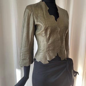May include: A green leather jacket with a scalloped hem and three-quarter sleeves.