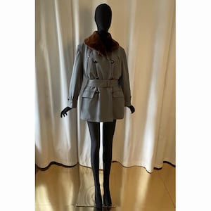 May include: A grey double-breasted coat with a brown fur collar and a belt. The coat has two large pockets on the front and a button closure.