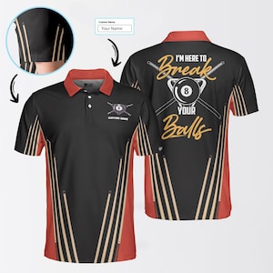 May include: Black and red polo shirt with a billiards theme. The shirt features a design with pool cues and the text "I'm here to break your balls." The front has a logo with a pool ball and crossed cues. The shirt has a red collar and accents.