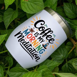 May include: White stainless steel tumbler with a colorful graphic that says "Coffee is my morning meditation".