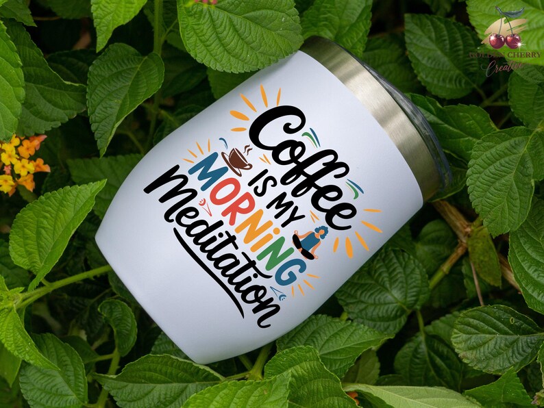 May include: White stainless steel tumbler with a colorful graphic that says "Coffee is my morning meditation".