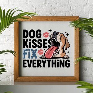 May include: A framed print with the text "DOG KISSES FIX EVERYTHING" in black and blue. The image features a cartoon dog with its tongue out. The frame is made of wood.