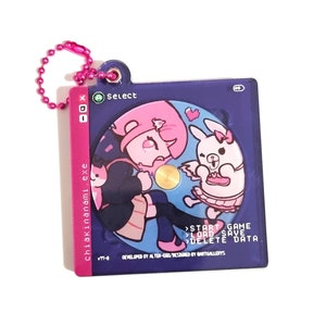 May include: A square, purple keyring with a pink ball chain. The keyring features a cartoon illustration of a girl and a bunny. Text on the keyring includes "chiakinanami.exe" and game options like "START GAME".