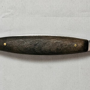 May include: A silver melon baller with a wooden handle. The handle has two brass accents. The tool is designed for scooping out melon balls.