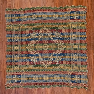 May include: A colorful woven tapestry with intricate patterns in shades of red, blue, green, and gold. The tapestry features a central design with repeating motifs of flowers and geometric shapes.