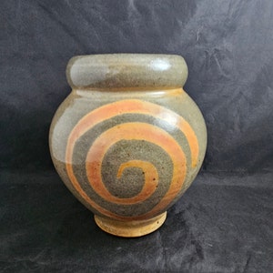 May include: A gray ceramic vase with a spiral design in orange and brown.