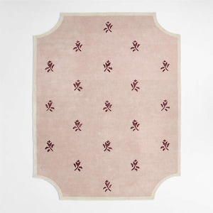 Puede incluir: Una alfombra rectangular con fondo rosa claro y borde crema. La alfombra presenta un patr&oacute;n repetido de motivos florales rojo oscuro. La forma de la alfombra tiene un borde decorativo y curvado.
