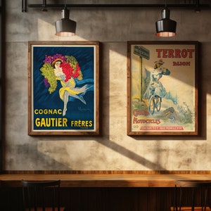 May include: Two vintage posters hanging on a wall. The left poster is blue with a woman holding grapes and the text "Cognac Gautier Frères France". The right poster is red, white, and blue with a woman riding a bicycle and the text "Cycles Motocycles Terrot Dijon".