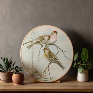 May include: A round wall decor featuring a painting of three birds perched on branches. The birds are brown, white, and pink with red accents. The background is a light blue with white accents.