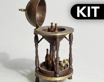 以下が含まれることがあります： ダークブラウンの木製でゴールドのアクセントが施された、地球儀型のミニチュアバーキャビネット。上部が開いて収納スペースが現れます。下段には小さな茶色のボトル数本とゴールドのゴブレットが2つ置かれています。黒いボックスの中にKITという文字があります。