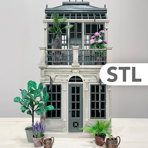 May include: A miniature two-story building with a balcony, windows, and a door. The building is painted in shades of gray and white, with green plants and pink flowers. The word "STL" is visible on the right side.