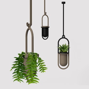 Könnte beinhalten: Drei hängende Pflanzgefäße in verschiedenen Braun- und Schwarztönen. Jedes Pflanzgefäß hat ein einzigartiges Design, eines davon enthält eine üppige grüne Pflanze. Die Pflanzgefäße sind von der Decke abgehängt und bieten eine moderne, minimalistische Ästhetik.