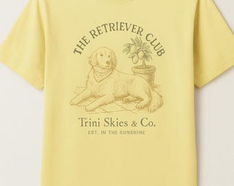 Puede incluir: Camiseta amarilla con un gráfico de un perro sentado junto a un limonero. El texto "The Retriever Club" está por encima del perro y "Trini Skies & Co. Est. in the Sunshine" está por debajo del perro.