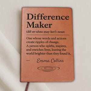 Könnte beinhalten: Ein braunes Notizbuch mit den schwarzen Worten "Difference Maker". Die Definition von "Difference Maker" ist unter dem Titel abgedruckt. Der Name des Autors, Emma Collins, ist unten abgedruckt.