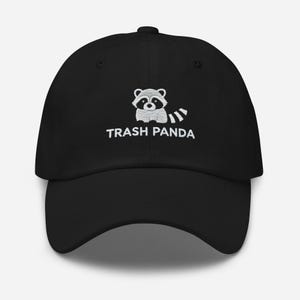 May include: Black baseball cap with a white embroidered raccoon and the text "Trash Panda".