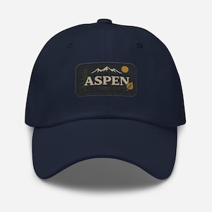Könnte beinhalten: Eine marineblaue Baseballkappe mit einem gestickten Aufnäher, auf dem "ASPEN" mit einer Bergkette, einem Baum, einer Sonne und einem Blatt steht.