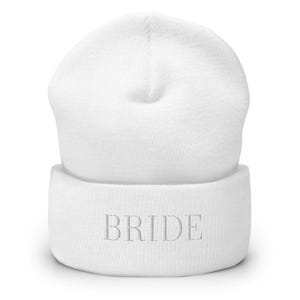 Puede incluir: Gorro de punto blanco con la palabra "BRIDE" bordada en plata en el puño.