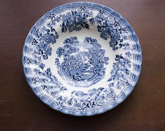 May include: A blue and white porcelain bowl with a floral pattern. The bowl has a scalloped edge and a raised rim.