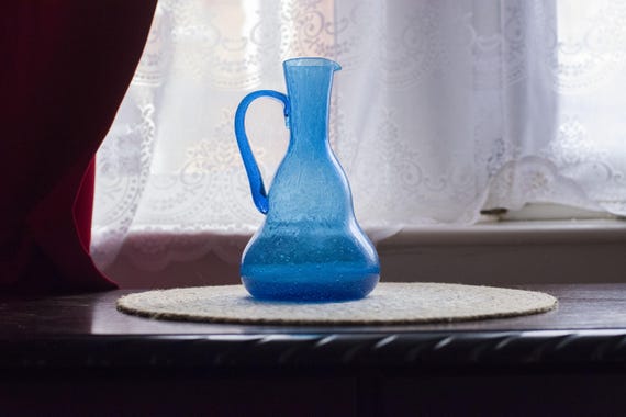 Blue glass jug or pitcher with a handle and a pour spout, blue bubble glass, soda-lime glass, decorative glass, hand blown glass