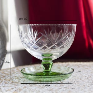 May include: A clear glass bowl with a green base and a matching green saucer. The bowl has a cut glass design and measures 10.5 inches in diameter and 9.5 inches in height.