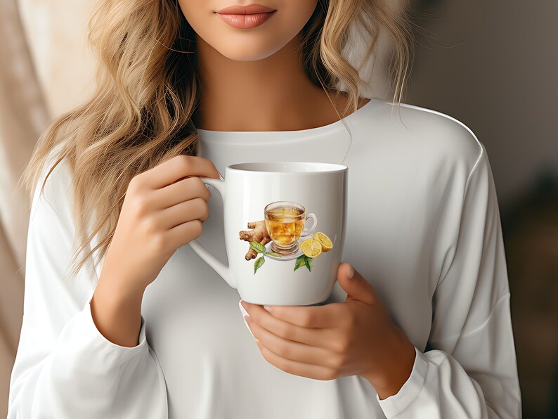 May include: White ceramic mug with a watercolor illustration of a glass of ginger tea with lemon slices. The mug is being held by a person.