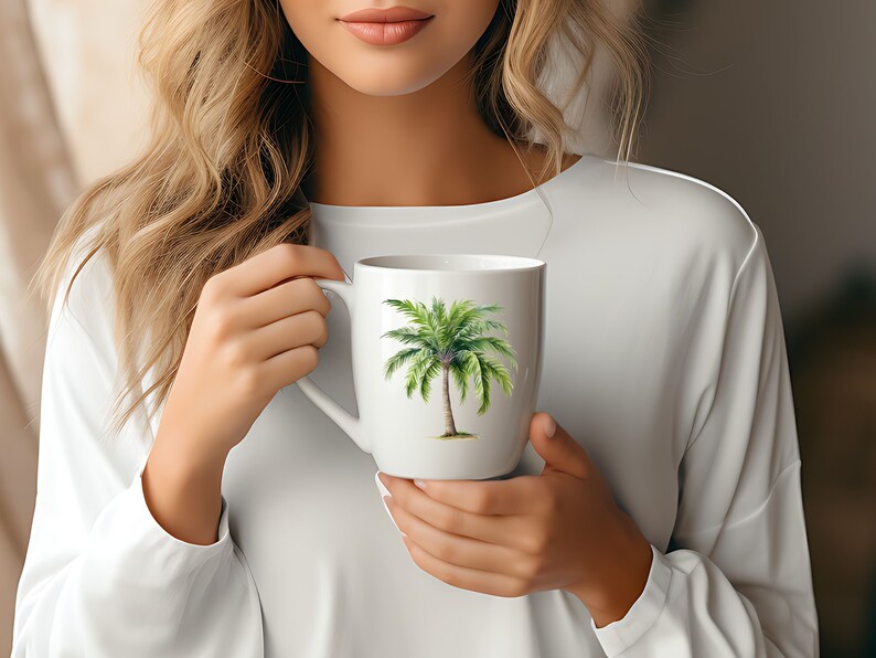 May include: White ceramic mug with a green palm tree design. The mug is being held by a person.