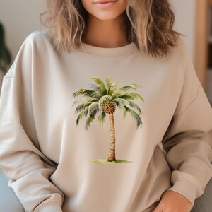 May include: A beige sweatshirt with a watercolor illustration of a palm tree on the front.
