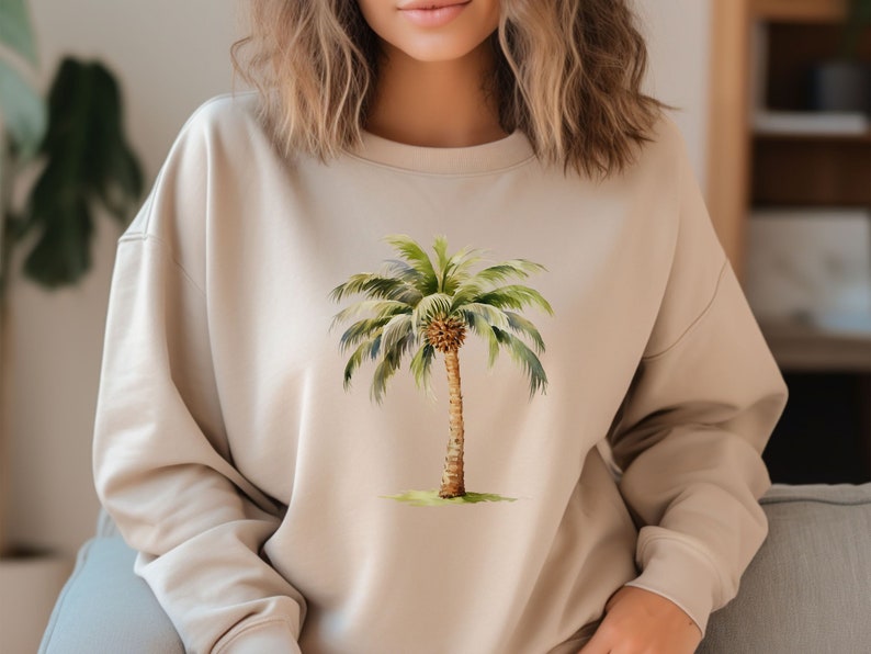 May include: A beige sweatshirt with a watercolor illustration of a palm tree on the front.
