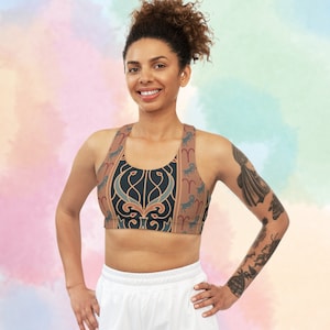 以下が含まれることがあります： 茶色、金色、青色の星座柄の黒いスポーツブラを着た女性。ブラはレーサーバックスタイルで、伸縮性のある快適な生地で作られています。