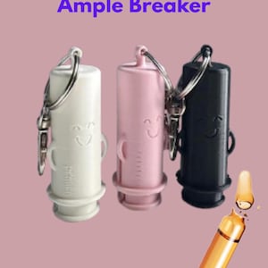 May include: Three ampoule breakers in white, pink, and black, each with a smiling face design and a keychain attachment. The text "Ample Breaker" is displayed above the breakers. An orange ampoule is also shown.