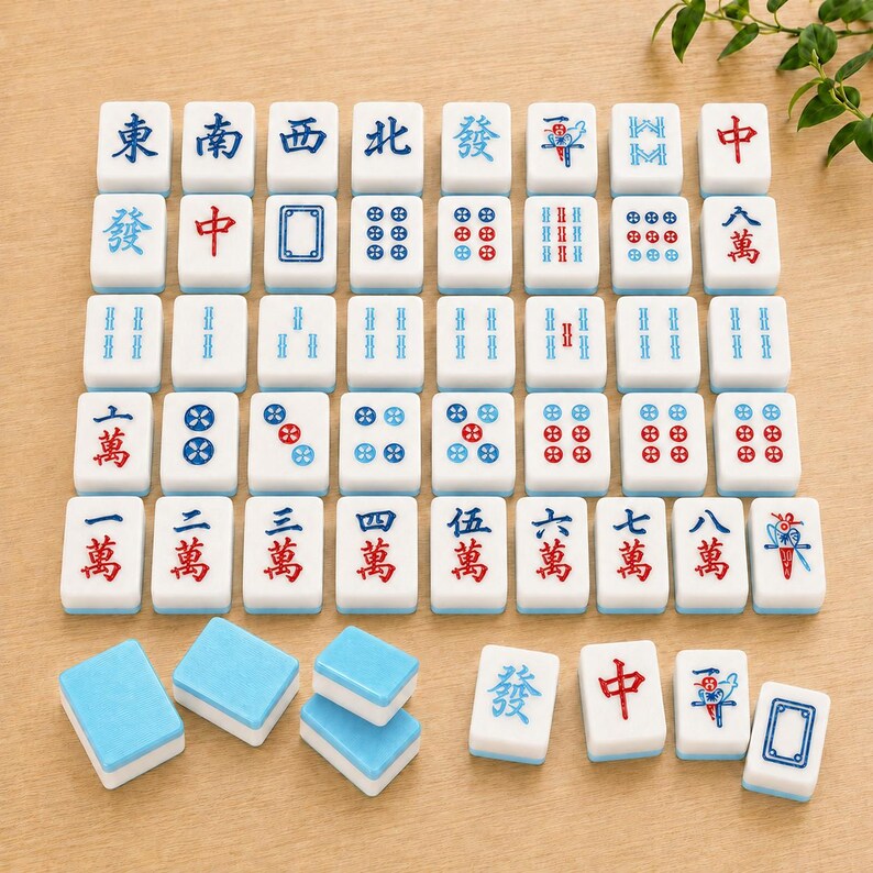 May include: A collection of white mahjong tiles with blue and red engraved characters, symbols, and numbers. The set includes a grid of upright tiles and several loose tiles placed face-up and face-down, displaying various suits and honors.
