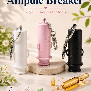 May include: Three ampule breakers in white, pink, and black, each with a smiling face design and a keychain attachment. The text "Ampule Breaker" and "your tiny protector" are displayed above the products. The image also shows an ampule.