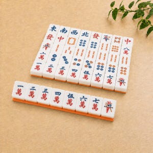 May include: A set of white rectangular Mahjong tiles featuring engraved characters and symbols in red, blue, and green ink. The tiles are arranged in a grid and a single row, displaying various numerical values, directional indicators, and decorative patterns.