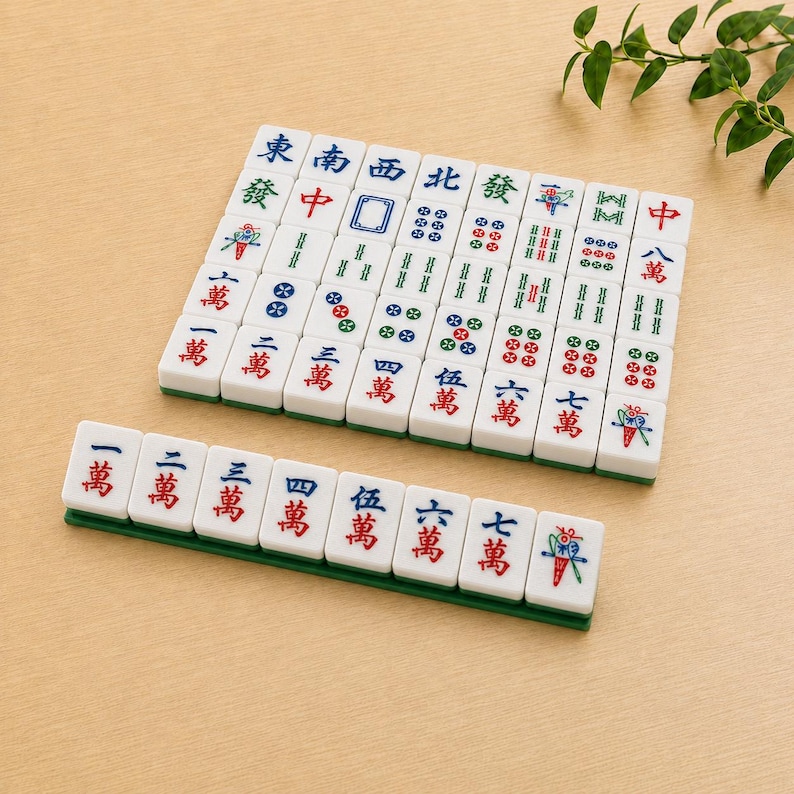 May include: A set of white rectangular Mahjong tiles featuring various colorful Chinese characters, numbers, and symbols in red, blue, and green ink. The tiles are arranged in a grid formation with a single row placed on a green rack in front.
