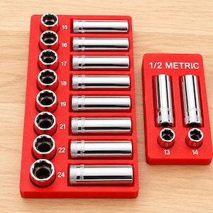 May include: A set of chrome-plated steel socket tools organized in two red plastic trays. The larger tray holds sizes 15 through 24, while the smaller tray is labeled 1/2 METRIC and contains sizes 13 and 14. Each socket features a knurled base.