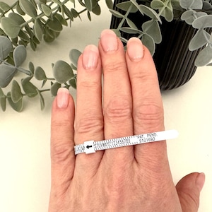 May include: A white plastic ring sizer with black markings and the text "PAT. PEND. 9101683".