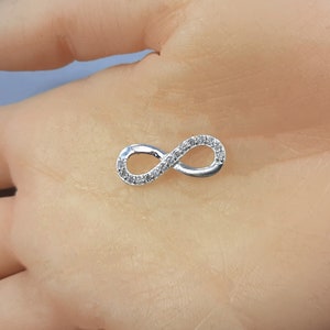 May include: A silver infinity symbol charm with small clear cubic zirconia stones set around the edges.