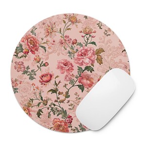 May include: Round mouse pad with a floral design featuring pink and red roses, green leaves, and a white computer mouse. The mouse pad has a light pink background with a subtle pattern.