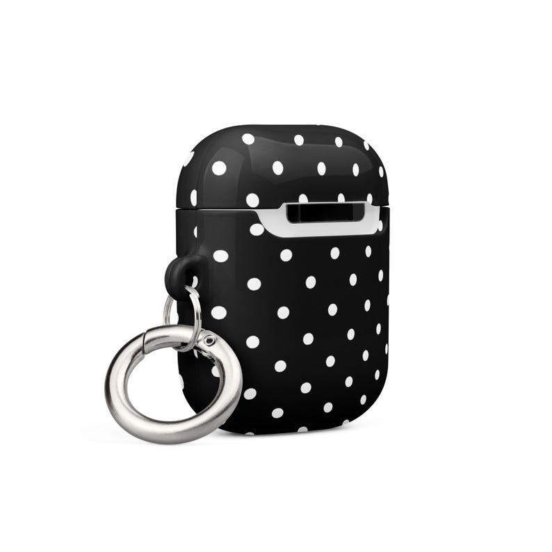 May include: Black and white polka dot silicone case for AirPods with a silver metal carabiner.