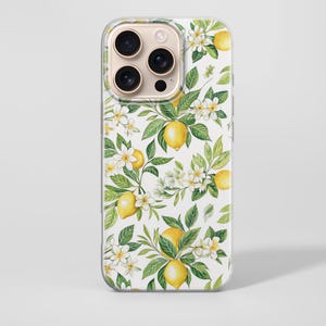 Puede incluir: Funda transparente para teléfono con un diseño de limones y flores. El diseño incluye limones amarillos, flores blancas y hojas verdes sobre un fondo blanco. La funda tiene un borde transparente y un recorte para la cámara.