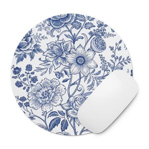 May include: A round white mousepad with a blue floral design and a white computer mouse. The floral pattern features detailed blue flowers, leaves, and vines on a white background. The mouse is a sleek, modern design.