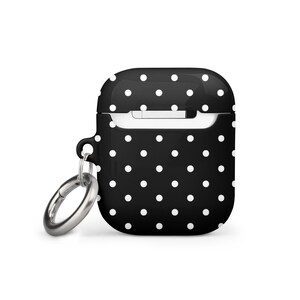 May include: Black and white polka dot silicone case with a silver keychain for Apple AirPods.