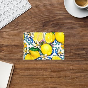 May include: A colorful illustration of lemons and flowers on a white background with blue and green accents. The lemons are arranged in a pattern and some are cut in half to show the yellow flesh.