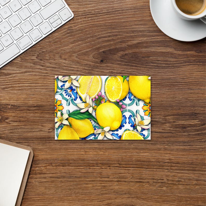 May include: A colorful illustration of lemons and flowers on a white background with blue and green accents. The lemons are arranged in a pattern and some are cut in half to show the yellow flesh.