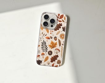 Puede incluir: Una funda transparente para teléfono con un diseño otoñal. El diseño incluye ilustraciones de hojas, setas, bellotas y rodajas de naranja en tonos marrón, naranja y beige. La funda está diseñada para un smartphone.