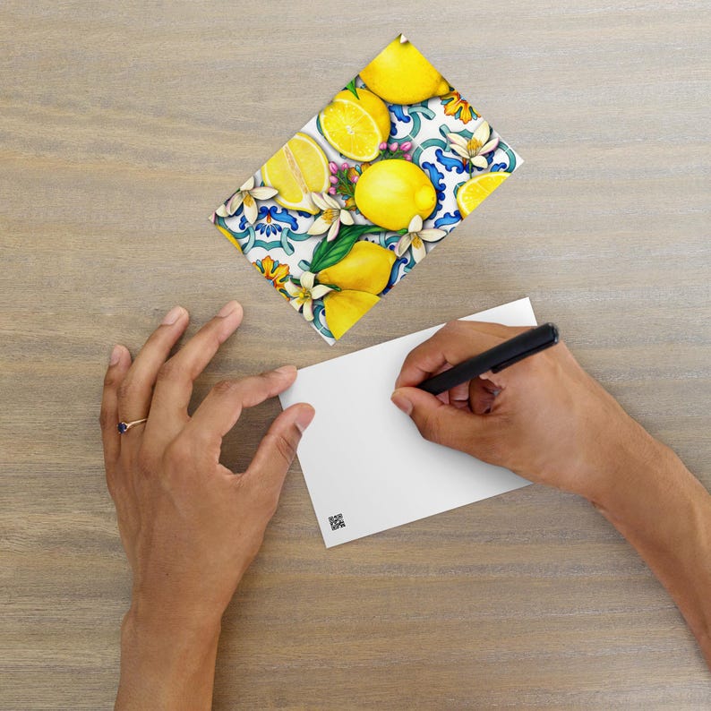May include: A postcard featuring a colorful illustration of lemons and flowers on a blue and white tiled background.