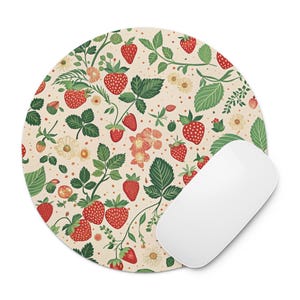 May include: A round mousepad with a cream background and a repeating pattern of strawberries, green leaves, and small white and yellow flowers. A white computer mouse is positioned on the right side of the mousepad.